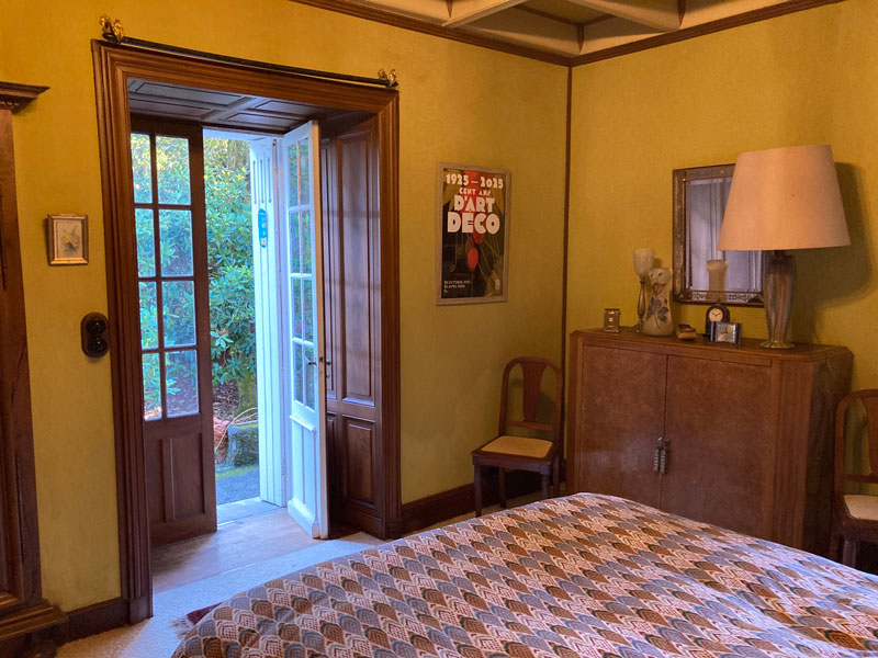 Chambre style art déco avec porte ouverte jardin.
