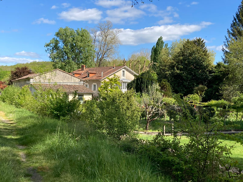 Maison française entourée de verdure et ciel bleu