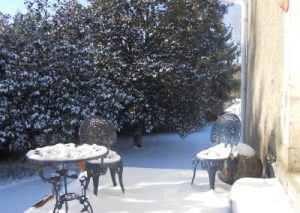 Terrasse enneigée avec chaises et table, jardin d'hiver.