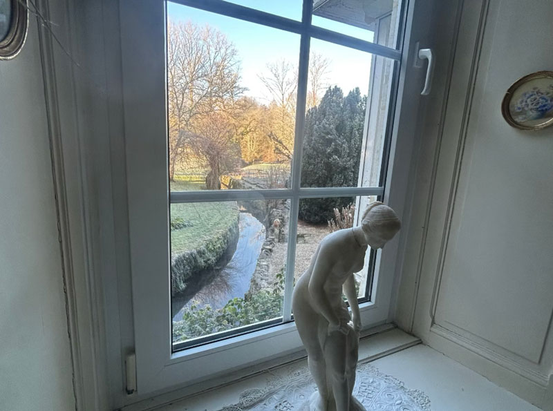 Statue près d'une fenêtre avec vue sur jardin.