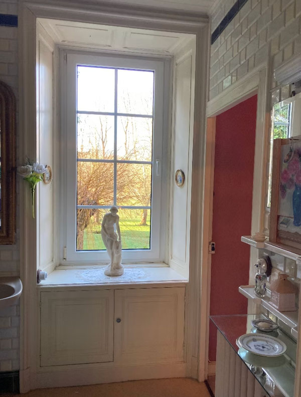 Salle de bain avec fenêtre et statue décorative.